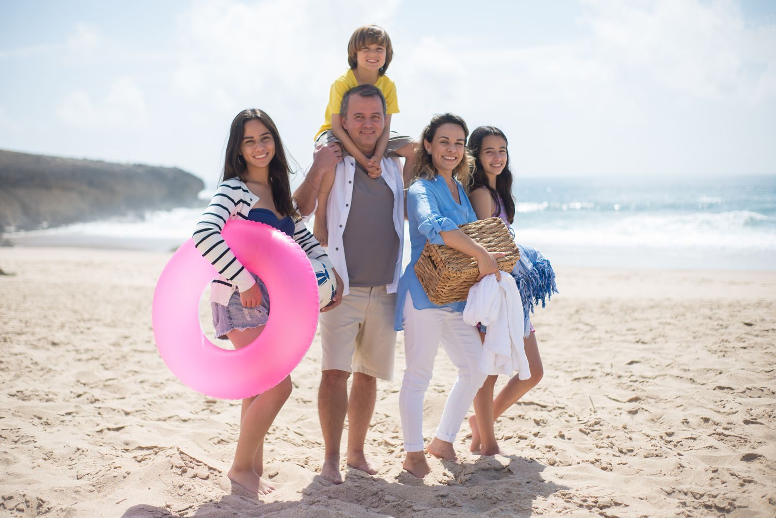Three generations of a family smiling together on a sunny beach, the travelers the best cruise for large family groups must suit