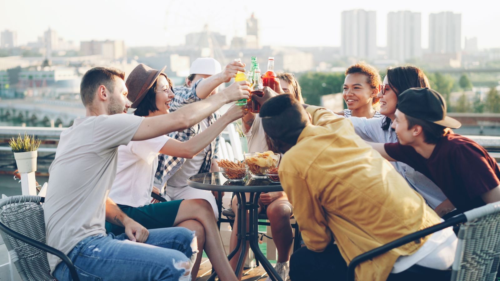 Friends raising their glasses around a table on a sunny rooftop, the spirit of the best cruise for a group of friends