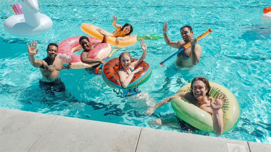 Friends waving from colorful floats in a swimming pool
