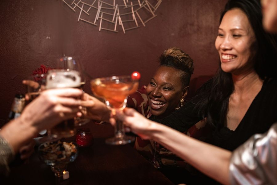 Friends clinking glasses in a warmly lit bar