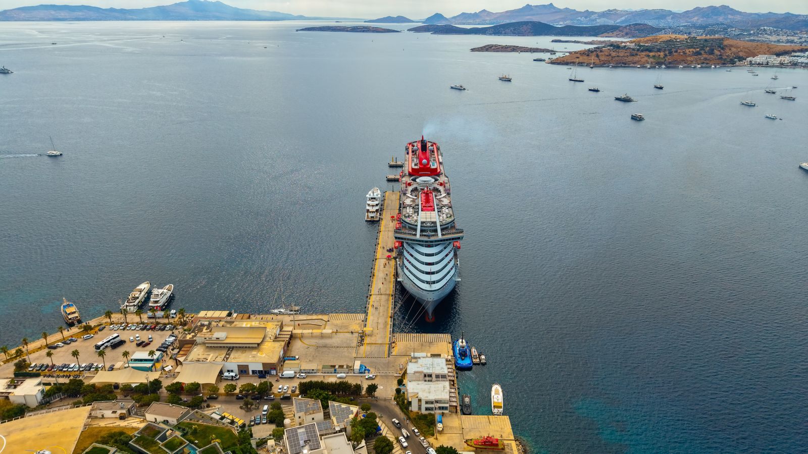 Aerial view of a large cruise ship docked at a pier in a wide bay